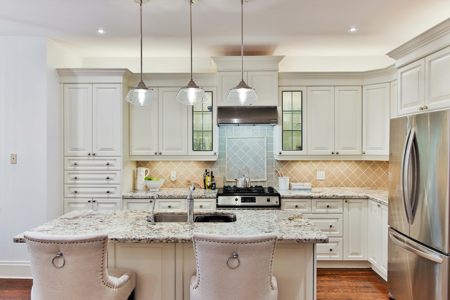 Warm transitional kitchen with detailed white cabinetry and a stone island